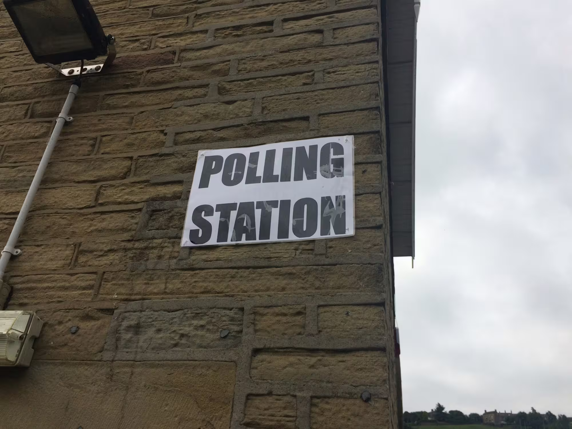 A photo of a sign saying 'Polling Station' on the side of a building