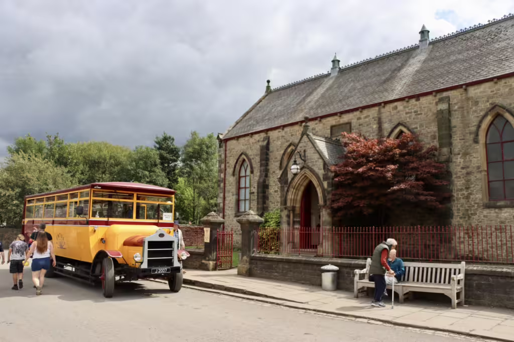 A old fashioned bus parked outside the church in the pit village at Beamish