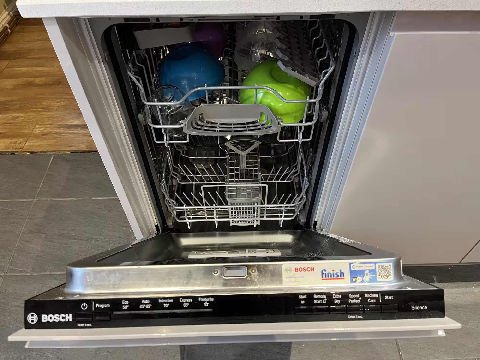 A photo of our dishwasher, with the door open and some crockery inside