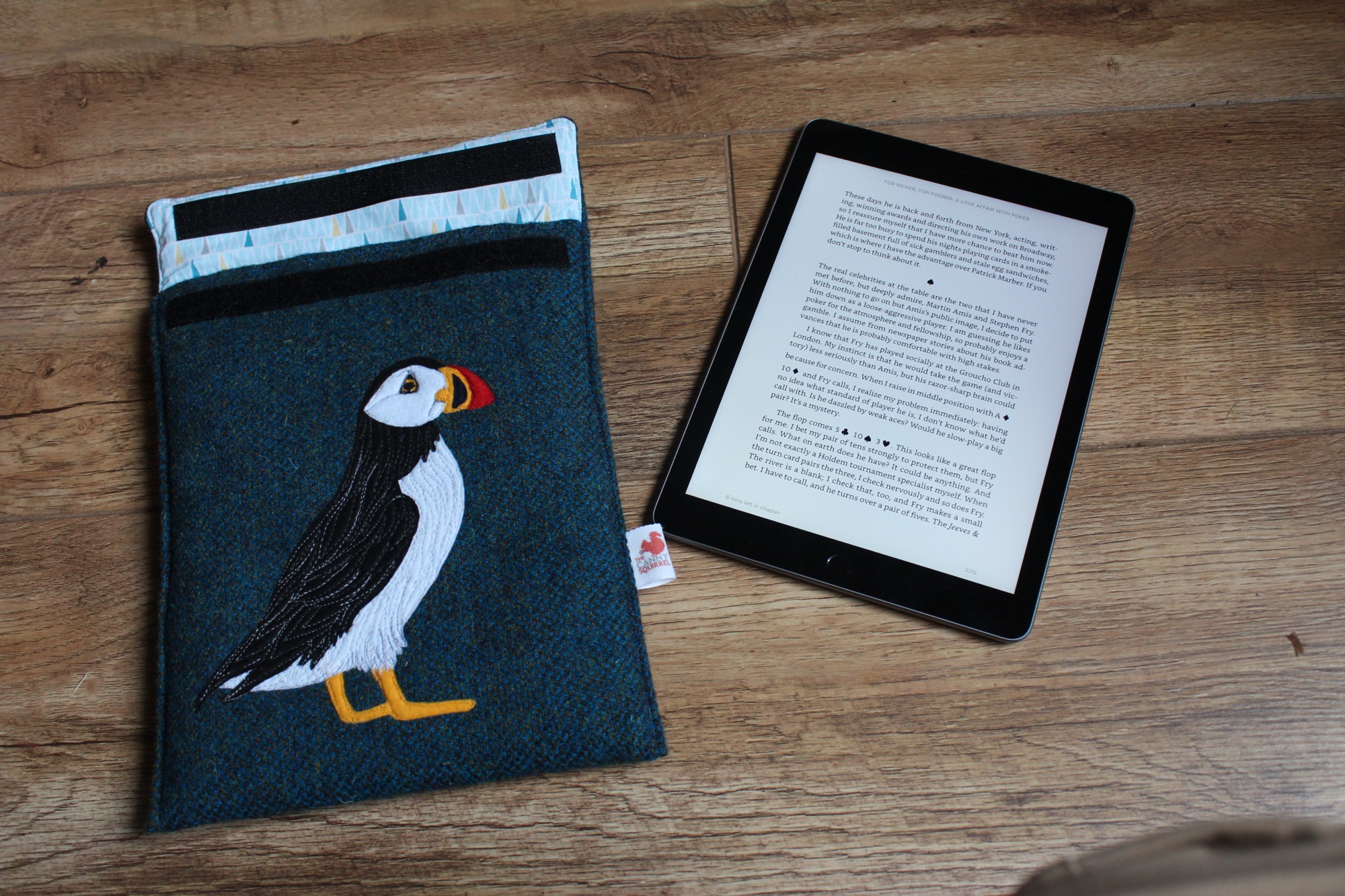 A photo of a new 6th generation iPad alongside a green case with an embroidered puffin on it