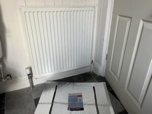A photo of a radiator in our bathroom, with a radiator reflector next to it.