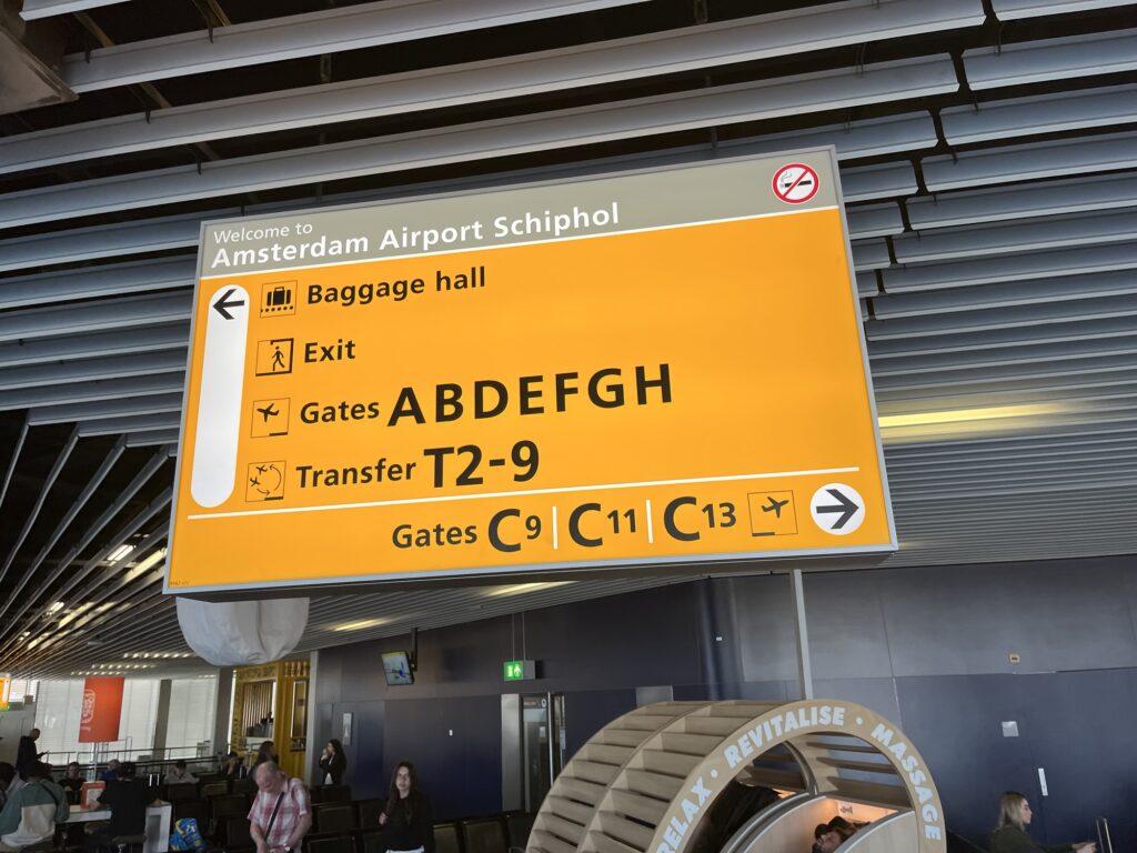A photo of a direction sign at Amsterdam Schiphol Airport
