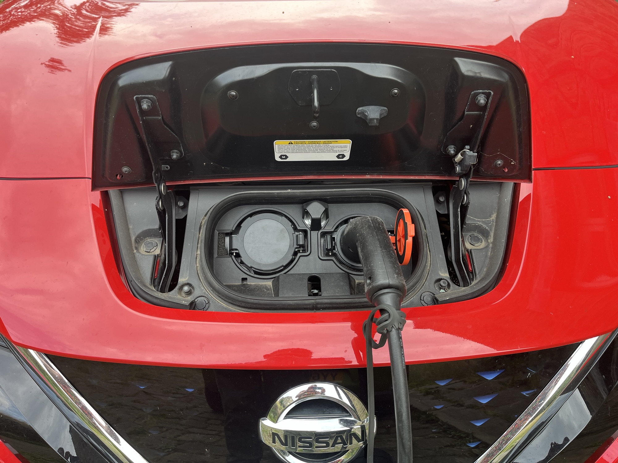 A photo of my Nissan Leaf, with the car charging port open and a Type 2 cable plugged in.
