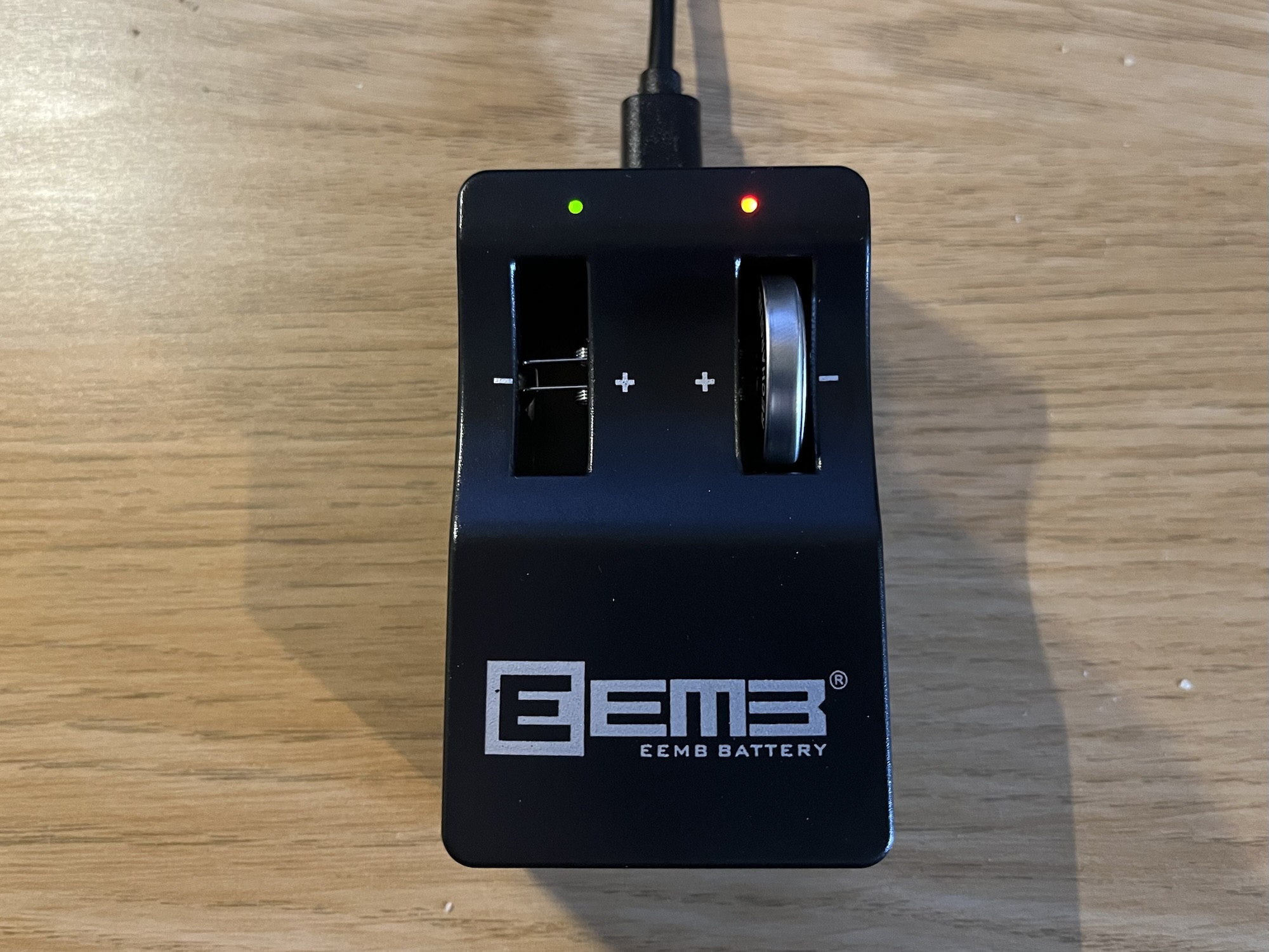 A photo of a button battery charger with a LIR2450 battery inserted.