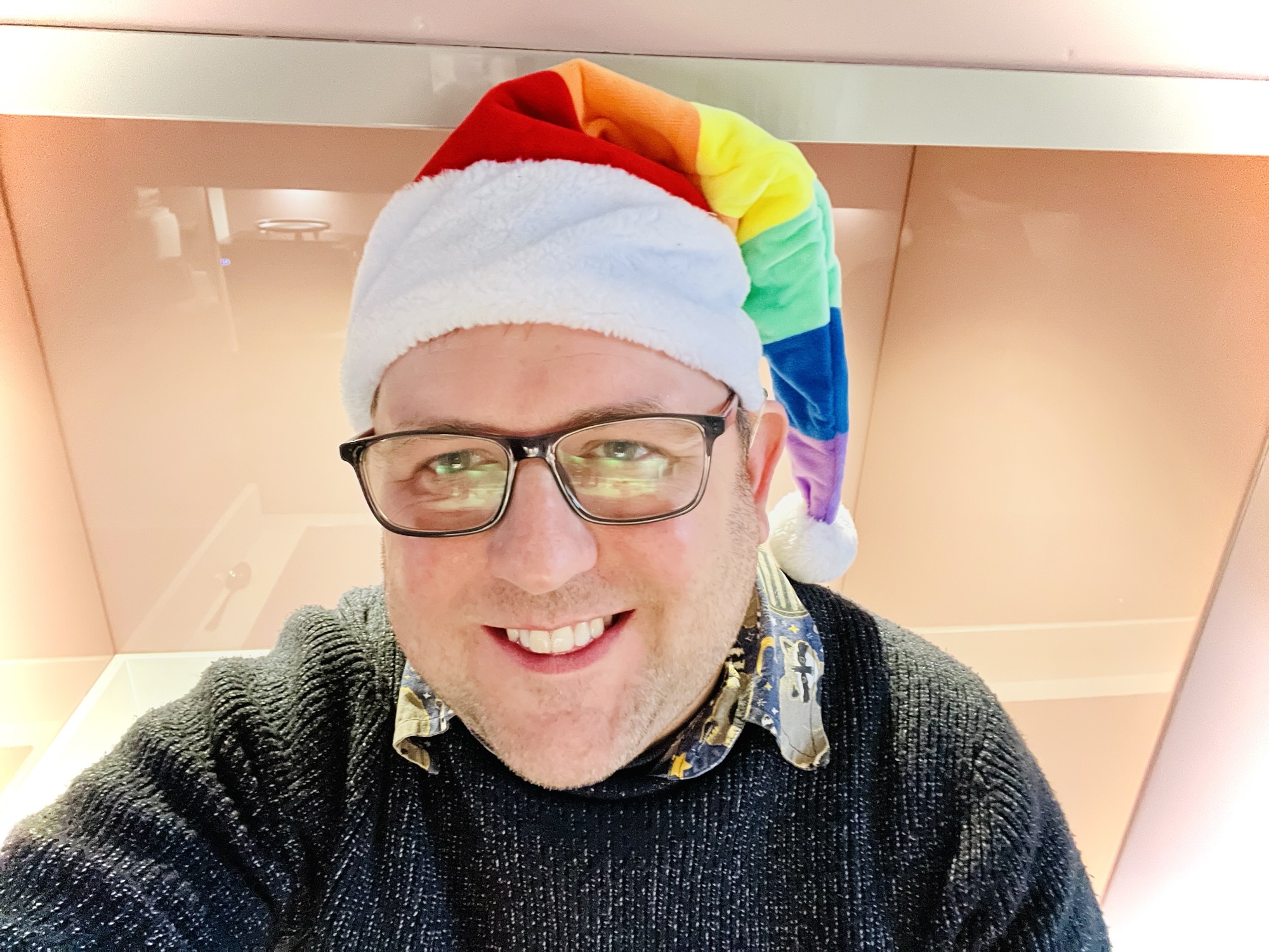 A photo of me wearing a rainbow santa hat