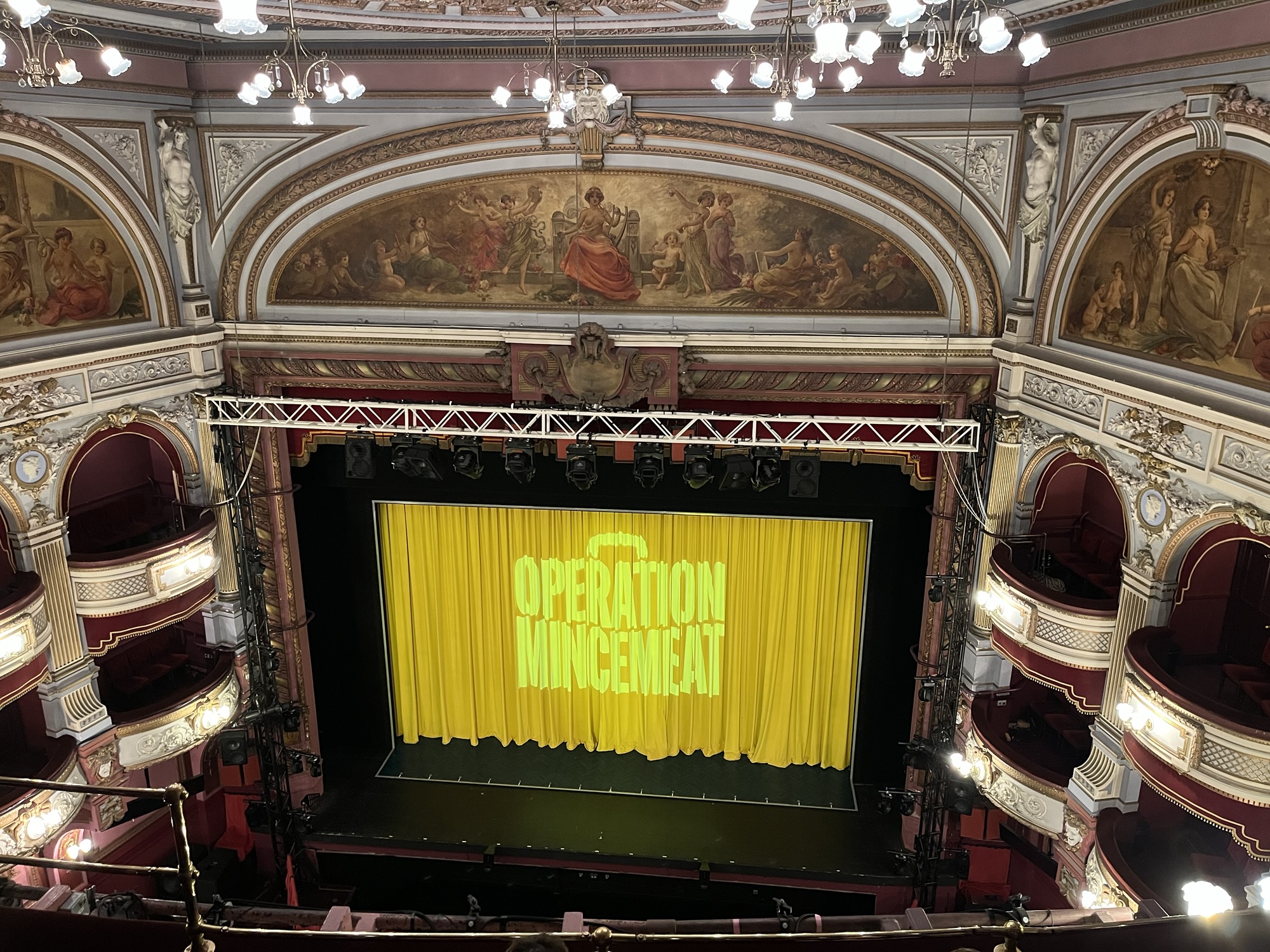 A photo of the inside of the Alhambra Theatre in Bradford showing the logo for Operation Mincemeat on the curtains whilst we were waiting for the show to start.
